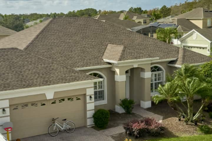 Brown GAF Timberline HDZ shingles on a beige stucco home.