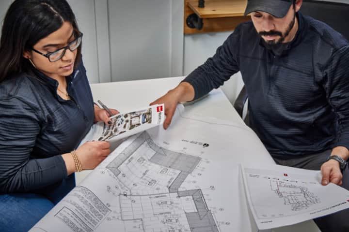 Man and woman reviewing GAF QuickMeasure aerial roof reports 