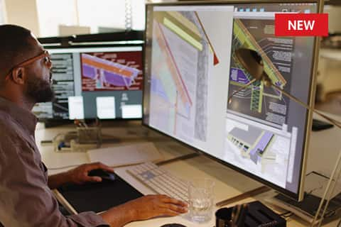 Man in front of computer screens working with GAF architect resources to create commercial roof designs