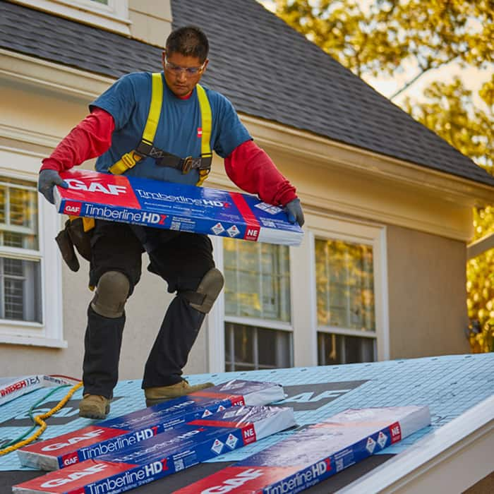 roofer laying packages of Timberline HDZ on top of roof