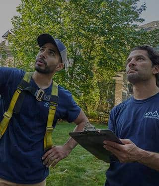 two roofers assessing storm damage to a roof