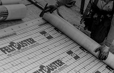 Shaded image of a GAF roofer installing a GAF roof deck protection underlayment sheet