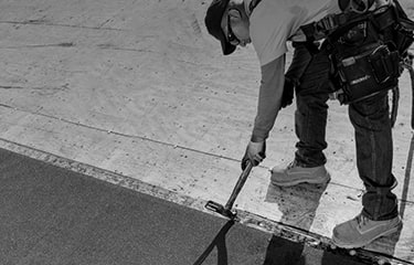 Shaded image of a GAF roofer installing GAF leak barrier on a residential roof