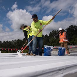 GAF contractors rolling coatings on a flat roof.