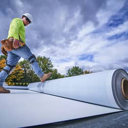 GAF contractor applying TPO roll to flat roof