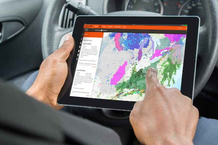 GAF certified contractor using GAF WeatherHub on a tablet in vehicle.