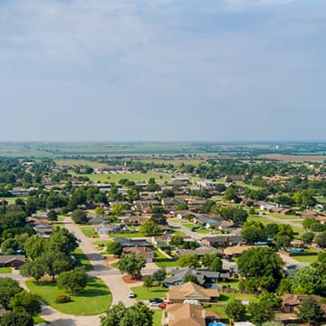 Aerial neighborhood image with houses, trees, and grass.